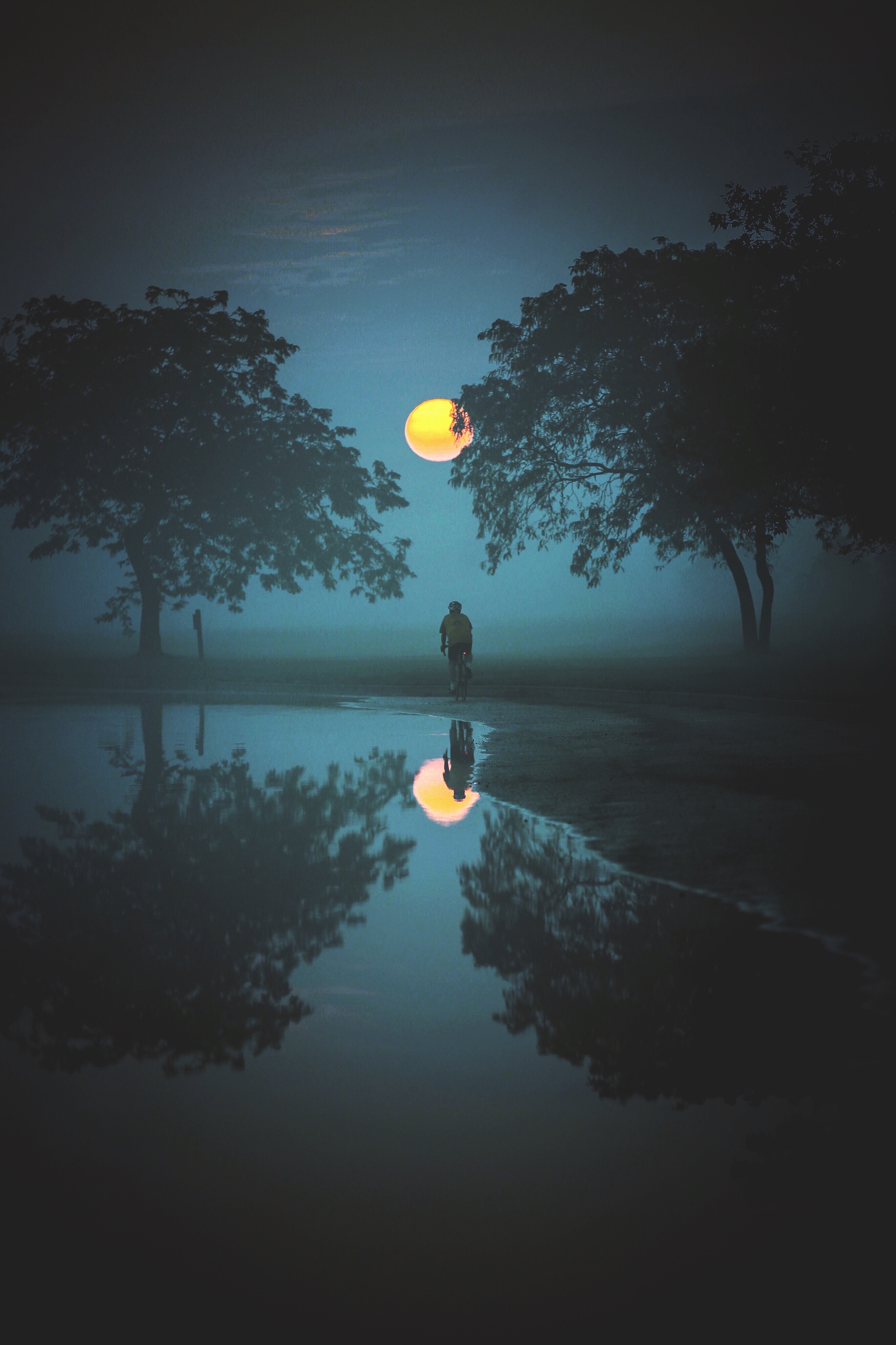 nighttime moon photo with man and moon reflected in pool of water